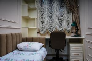 a bedroom with a bed and a desk and a chair at Learmara Apartment #2 in Samarkand