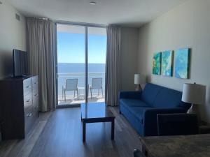 Sala de estar con sofá azul y vistas al océano en South Beach Biloxi Hotel & Suites, en Biloxi