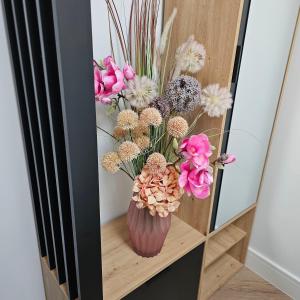 a vase filled with flowers sitting on a shelf at Trinity- New Modern Apartment with FREE on road parking in Girton