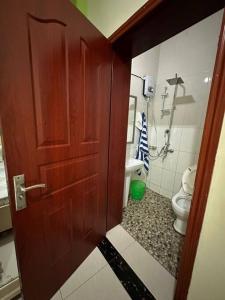 een badkamer met een toilet en een houten deur bij Private house in Kibagabaga in Kigali