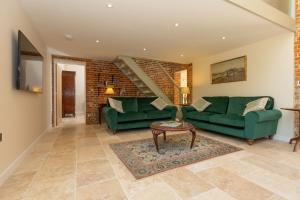 a living room with two green couches and a table at The Hay Loft in Swafield