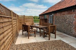 a patio with a wooden table and chairs at The Hay Loft in Swafield