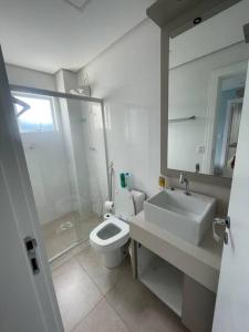 een witte badkamer met een wastafel en een toilet bij Vista para o Mar in Laguna