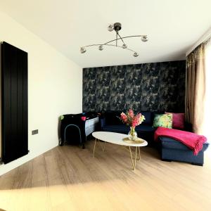 a living room with a blue couch and a table at Trinity- New Modern Apartment with FREE on road parking in Girton