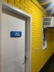 a white door with a blue sign next to a yellow brick wall at canto de Geriba in Búzios