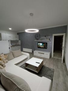 a living room with a white couch and a tv at Apartment Maska in Budva