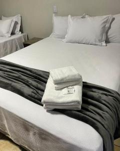 a bed with two towels sitting on top of it at Hotel Rio Jordão in Siderópolis