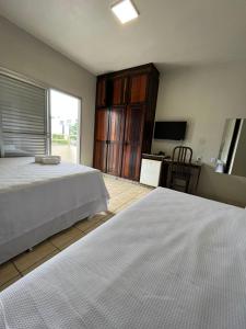 um quarto com 2 camas brancas e uma televisão em Hotel Rio Jordão em Siderópolis