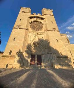 un grand bâtiment en pierre avec une tour d'horloge dans l'établissement Le Foch_Beziers Centre_wifi, à Béziers