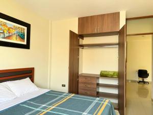 a bedroom with a bed and a closet and a desk at Exclusivo departamento en Chiclayo in Chiclayo