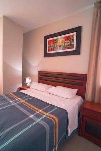 a bedroom with a bed and a picture on the wall at Exclusivo departamento en Chiclayo in Chiclayo