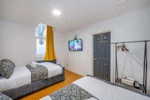 1 Schlafzimmer mit 2 Betten und einem TV an der Wand in der Unterkunft *F18GH* For relaxed & Cosy stay/Free Parking/WiFi in Leeds