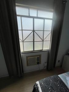 um quarto com uma grande janela e uma ventoinha em Suíte Hotel São José em Caxambu