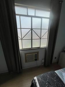 a bedroom with a large window with a fan at Suíte Hotel São José in Caxambu