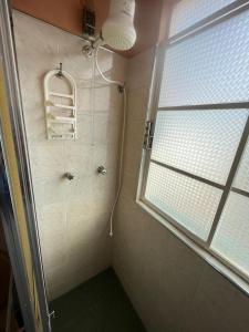 y baño con ducha y ventana. en Suíte Hotel São José en Caxambu