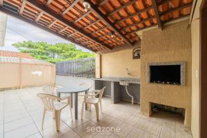 d'une terrasse avec une table, des chaises et une télévision. dans l'établissement Casa 3 quartos a 50m da praia Penha-SC EPS055, à Penha