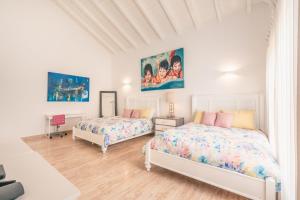 two beds in a bedroom with white walls at 4BR Villa w private pool at Lagunas Cap Cana in Punta Cana