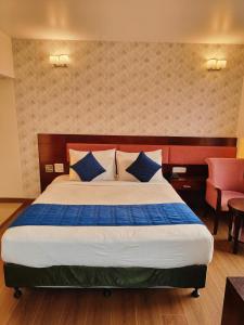 a bedroom with a large bed with blue pillows at RoseMallow Tavisha Hotel in New Delhi