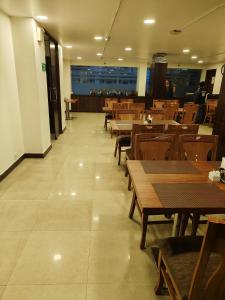 een eetkamer met houten tafels en houten stoelen bij RoseMallow Tavisha Hotel in New Delhi