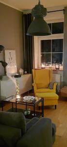Sala de estar con silla amarilla y mesa en Apartament DANI, en Nysa