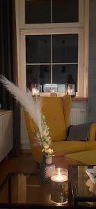 a living room with a yellow couch and a table with candles at Apartament DANI in Nysa