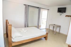 Hotel Caribe Coveñas في كوفيناس: غرفة نوم بسرير وملاءات بيضاء ونافذة