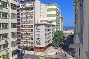 ein hohes weißes Gebäude in einer Stadtstraße mit Gebäuden in der Unterkunft Studio para 4 pessoas com vista mar em Copacabana in Rio de Janeiro
