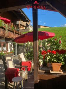 um pátio com cadeiras, um guarda-sol e flores em Bergwald em Alpbach