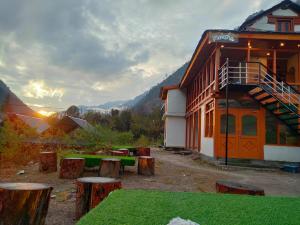 a building with a group of wooden stools in front of it at MOKSHA COTTAGES AND WOODHOUSE in Kasol