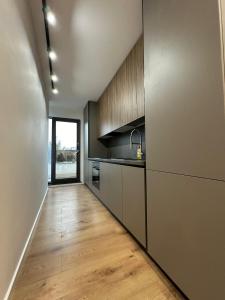 a kitchen with white cabinets and a wooden floor at Oasului Residence in Cluj-Napoca