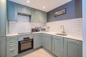 eine Küche mit blauen Schränken und einem Waschbecken in der Unterkunft 3 Bedroom 2 Bathroom I Super Central Location I Sleep 9 Guests in Brighton & Hove