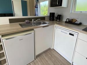 a kitchen with white cabinets and a sink at Chalet in Friesland near Nature Reserves in De Veenhoop