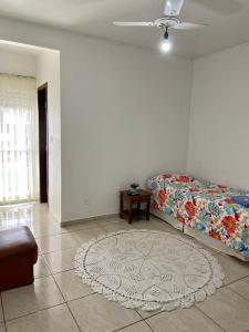 ein Wohnzimmer mit einem Bett und einem Teppich in der Unterkunft Espaço Verona apartamento econômico c/banheiro e sem café p/ 1 pessoa in Fazenda Rio Grande