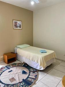 een slaapkamer met 2 bedden en een tapijt op de vloer bij Espaço Verona apartamento econômico c/banheiro e sem café p/ 1 pessoa in Fazenda Rio Grande