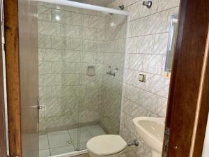 een badkamer met een douche, een toilet en een wastafel bij Espaço Verona apartamento econômico c/banheiro e sem café p/ 1 pessoa in Fazenda Rio Grande