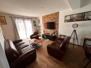 ein Wohnzimmer mit Ledermöbeln und einer Ziegelwand in der Unterkunft Maison chaleureuse tout confort in Amboise
