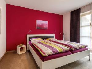 una camera con un letto e una parete con accento rosso di Holiday apartment Alpenstern a Ruhpolding