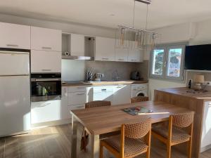 a kitchen with white cabinets and a wooden table at La Palmeraie 2 chambres in Sainte-Maxime
