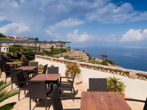 een patio met tafels en stoelen en de oceaan bij Hostal Sa Baronia in Banyalbufar