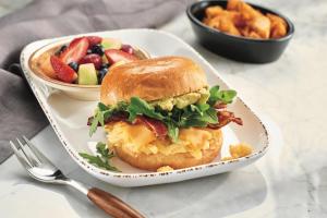 a breakfast sandwich on a plate with a bowl of fruit at Courtyard by Marriott Delray Beach in Delray Beach