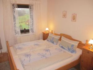 a bed with blue and white sheets and a window at Bohn - Apartment 2 in Gersfeld