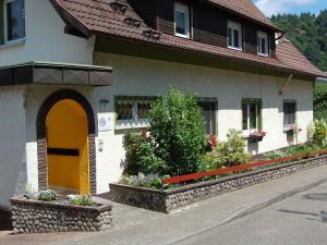 a building with a yellow door and some flowers at Holiday apartment holidays in the forest in Weisenbach