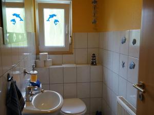 baño con lavabo y aseo y ventana en Holiday apartment holidays in the forest en Weisenbach