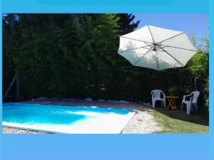 a white umbrella and a chair and a table and a pool at Las Azucenas in Ranchos