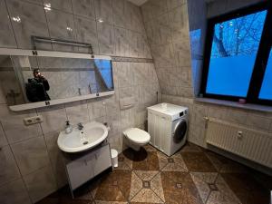 a man taking a picture of a bathroom with a toilet and sink at Villa Hirsch in Gera