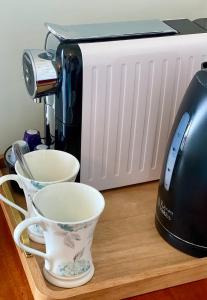 a coffee maker and two cups on a wooden table at East Beach Hotel in Eastbourne