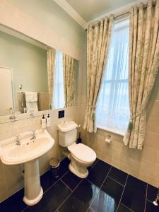a bathroom with a toilet and a sink and a window at East Beach Hotel in Eastbourne