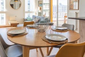 uma mesa de madeira com pratos e talheres em Bright apartment in Saint-Denis - Welkeys em Saint-Denis