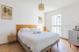 um quarto com uma cama grande e lençóis brancos em Bright apartment in Saint-Denis - Welkeys em Saint-Denis