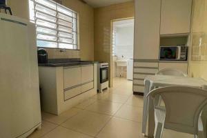 kuchnia z białymi urządzeniami oraz stołem i krzesłami w obiekcie Apartamento Confortável e Espaçoso UEM EL06 w mieście Maringá